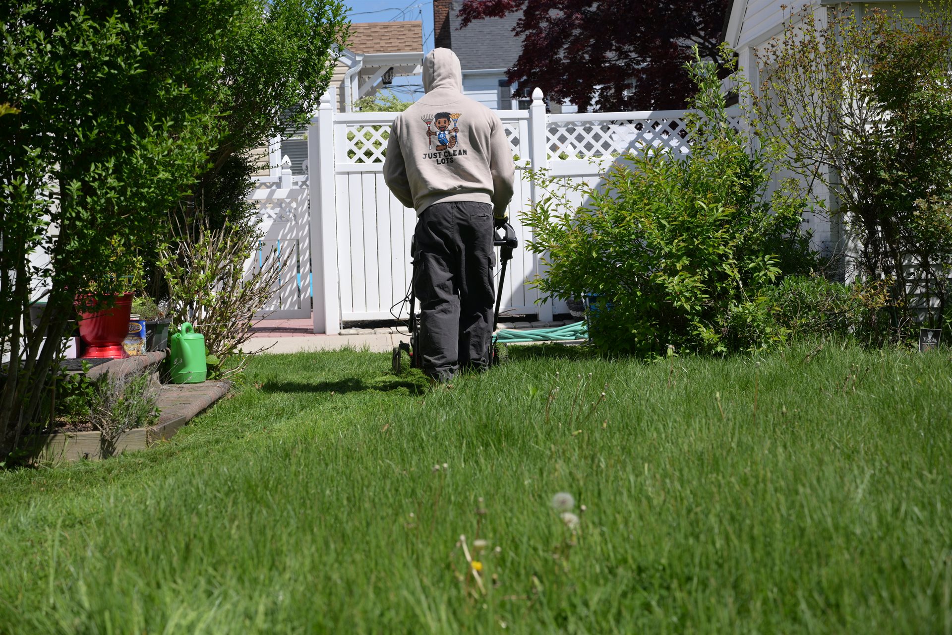 JCL crew member in branded hoodie edging a residential lawn