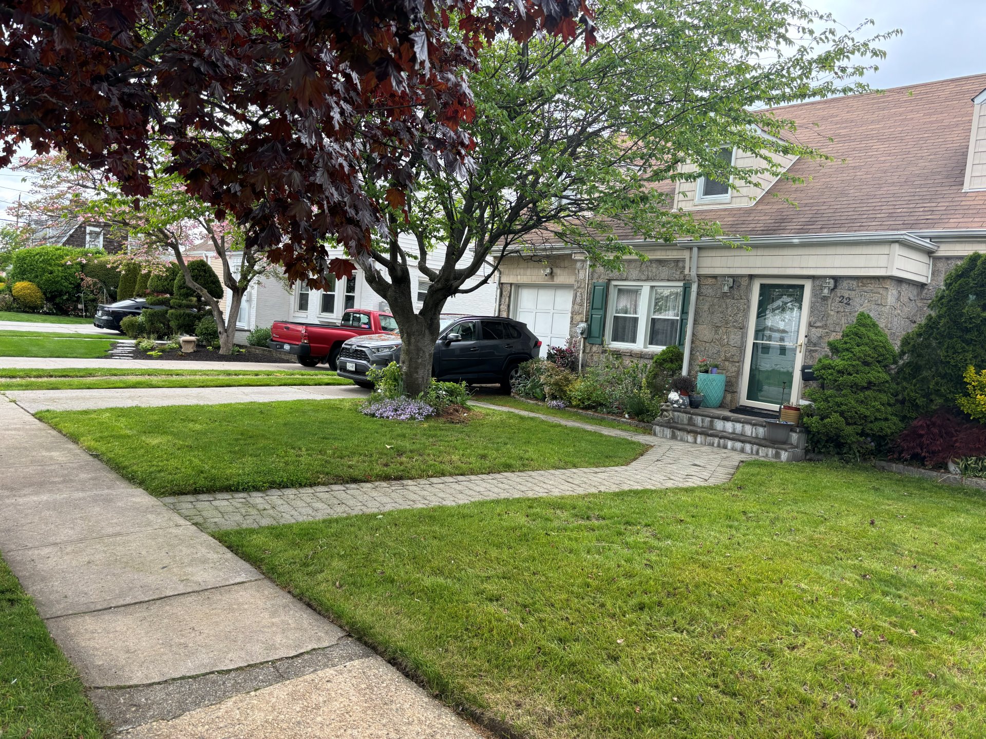 Brick residential home with manicured front lawn and trimmed beds