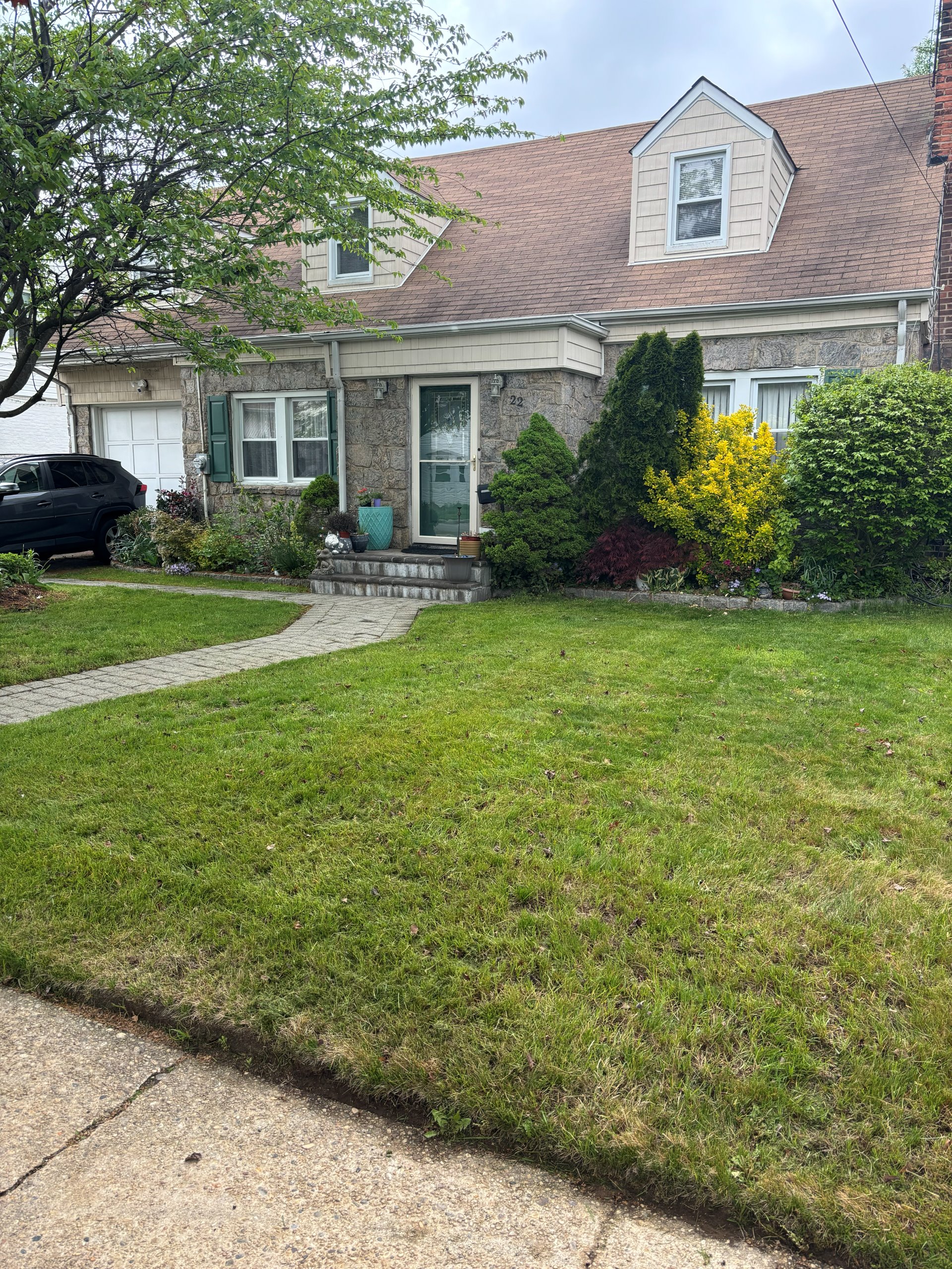 Cape Cod style home with manicured front lawn and stone walkway