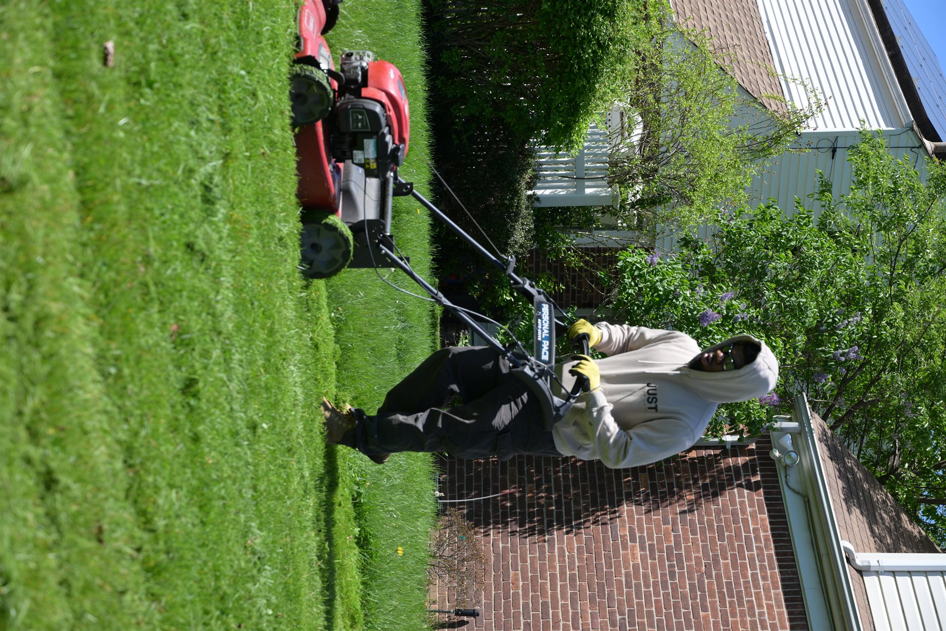 JCL crew mowing a residential backyard with a Honda mower